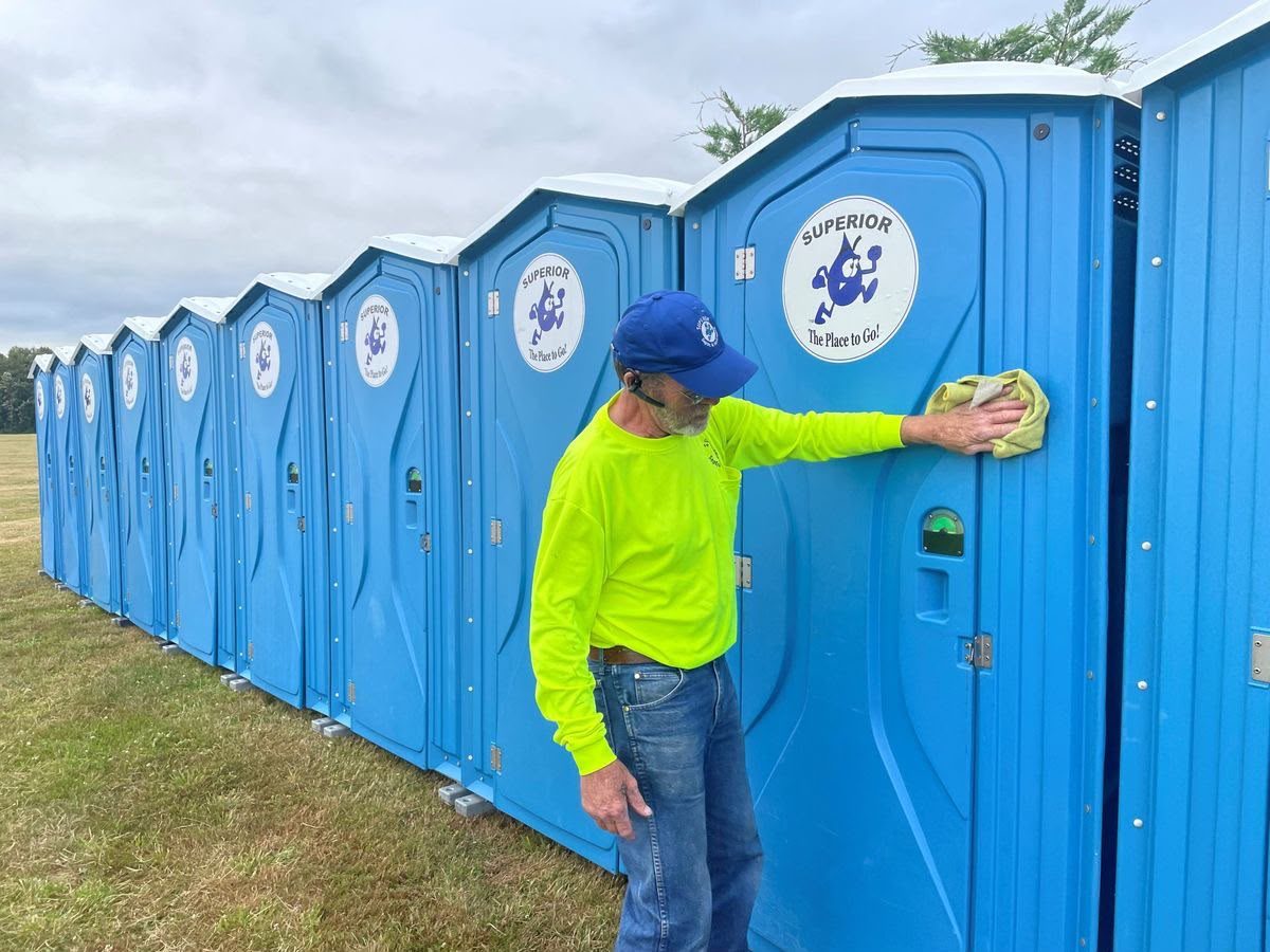 Worker beside a row of portable restroom units at a job site