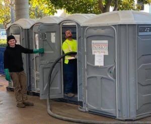 Technician servicing a portable restroom unit on an emergency call